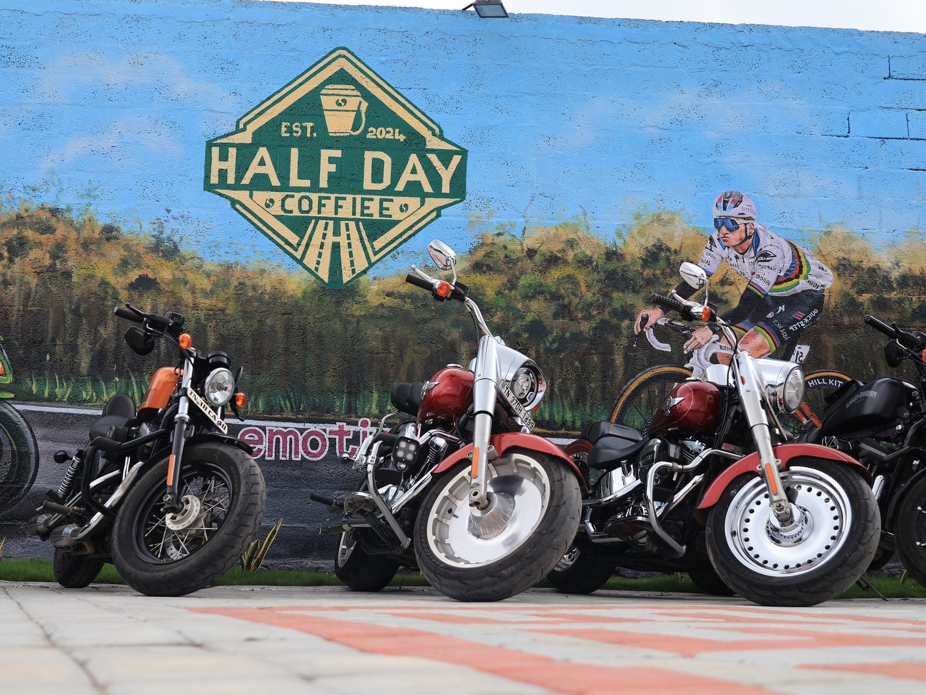 Motorcycles lined up against the mural at HalfDay Coffiee